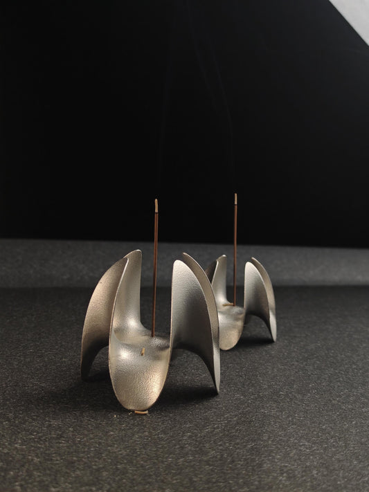 A sculptural incense holder crafted from aerospace-grade aluminum alloy, featuring a flowing cyberpunk-inspired form and a matte silver finish. Designed for modern interiors, meditation spaces, or futuristic decor setups.