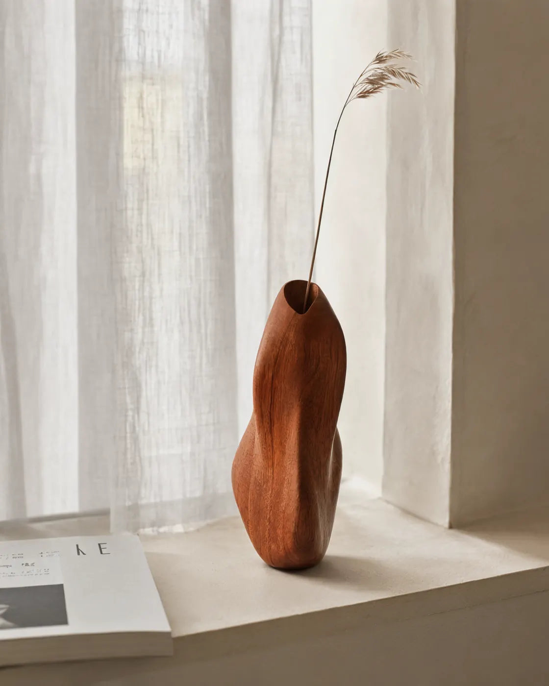 Wood diffuser with dried grass by a sheer curtain